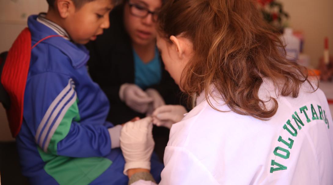 A child has his blood pressure checked by a high school student doing her summer medical internship abroad. A high school student checks a child’s blood pressure and gains clinical experience at her medical program in Peru.